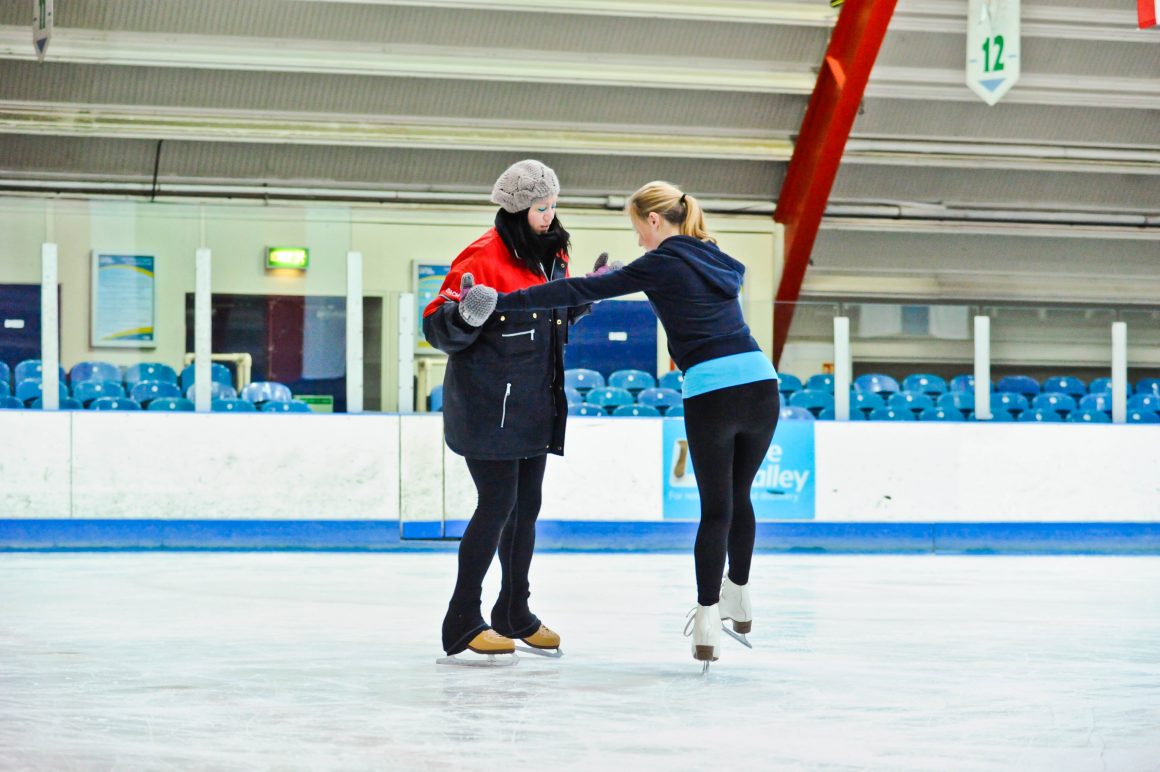 A woman enjoys an ice skating lesson